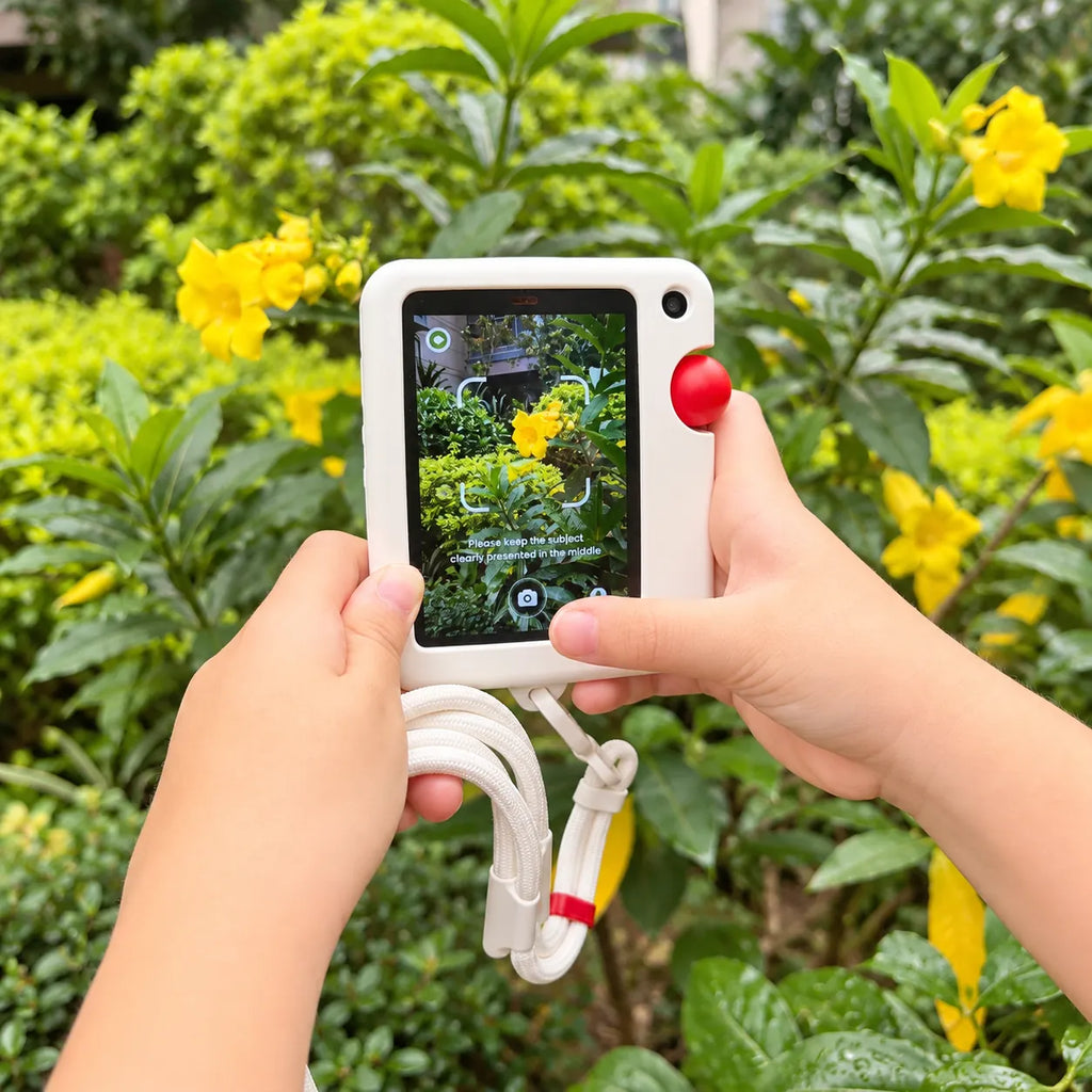 A child using the GigglePal Pocket camera to photograph yellow flowers in a garden.